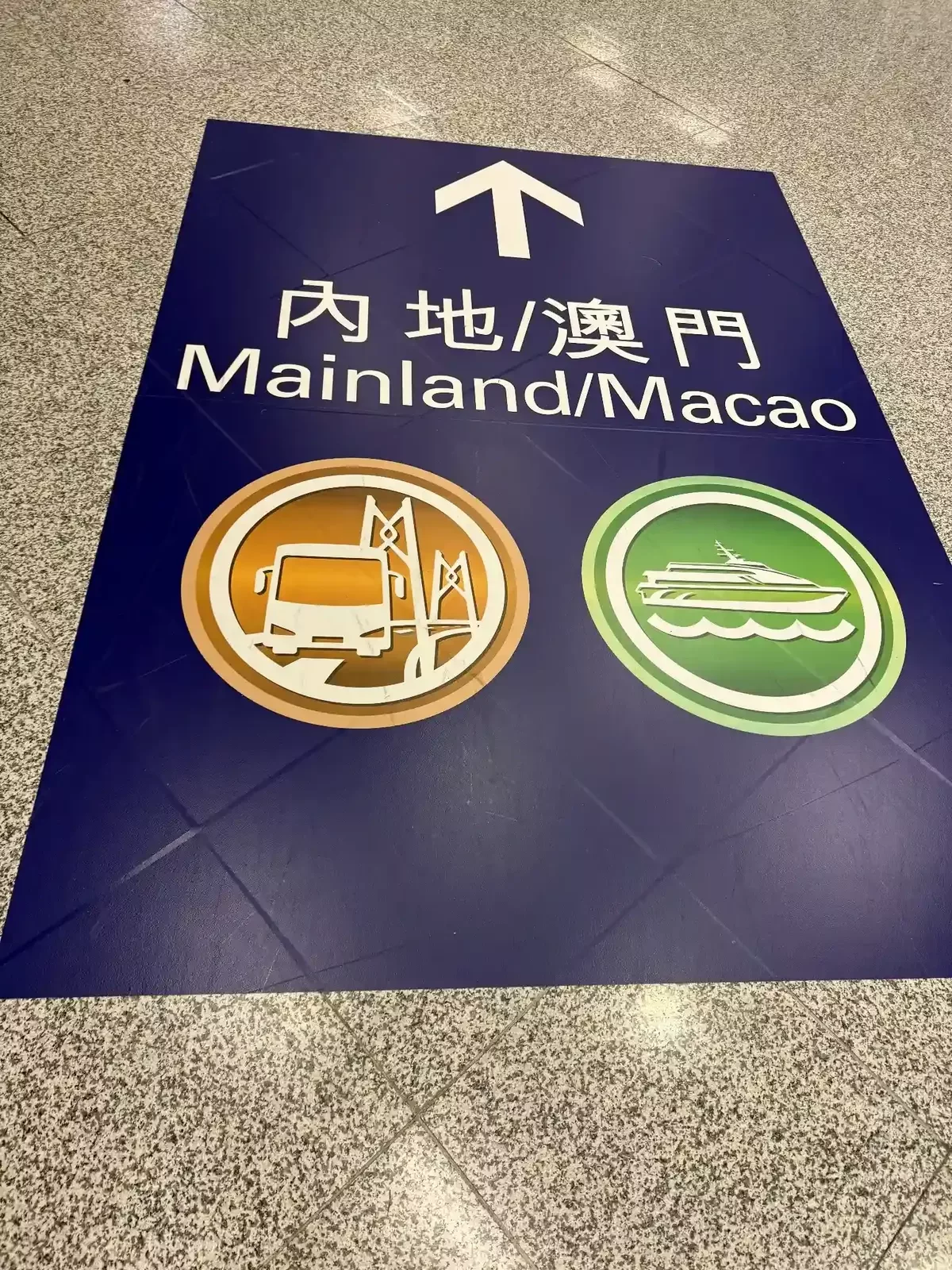Directional floor sign pointing to Mainland and Macau transfers at HKIA