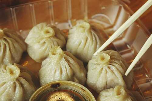 Close-up of xiao long bao soup dumplings with chopsticks and dipping sauce