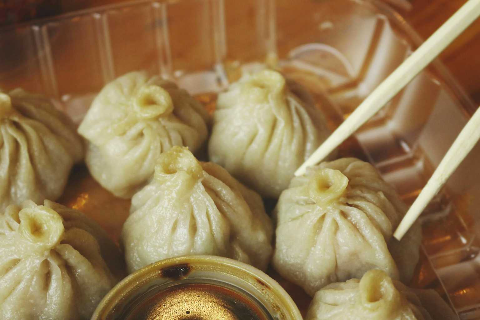 Close-up of xiao long bao soup dumplings with chopsticks and dipping sauce